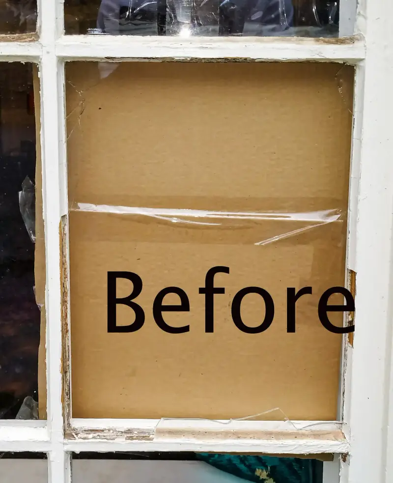 Broken window pane patched with cardboard before repair